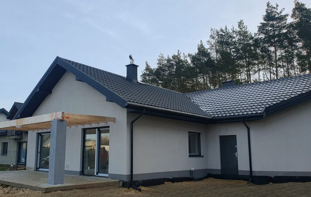 Parterowy dom z perlitu przy ul. Rokicińskiej w Łodzi, z grafitowym dachem i dużymi przeszkleniami